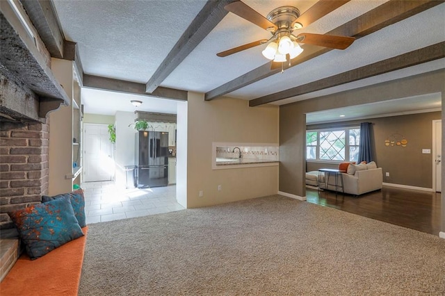 carpeted living room with beam ceiling, a textured ceiling, ceiling fan, and baseboards