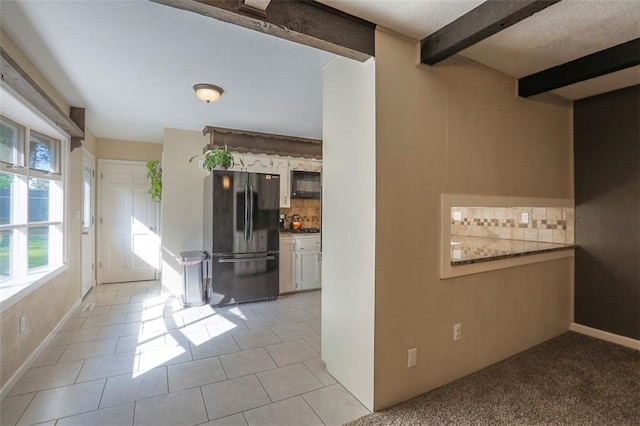 unfurnished room with beamed ceiling, light tile patterned flooring, baseboards, and a textured ceiling