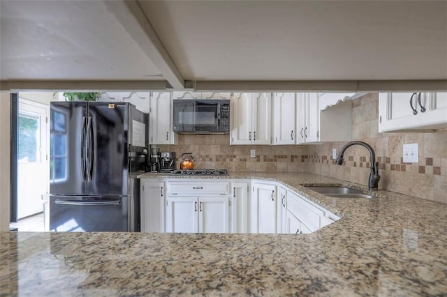 kitchen featuring black appliances, a sink, white cabinetry, tasteful backsplash, and light stone counters