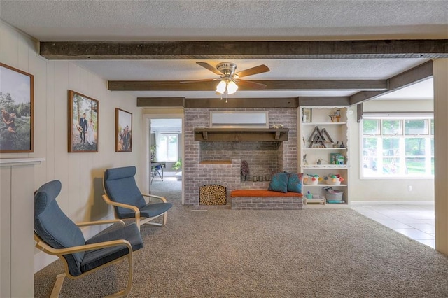 tiled living room featuring a textured ceiling, a brick fireplace, beamed ceiling, ceiling fan, and carpet