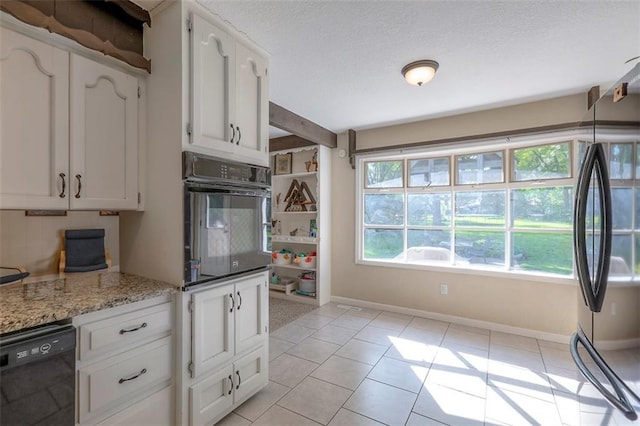 kitchen with black appliances, white cabinets, light tile patterned flooring, baseboards, and a textured ceiling