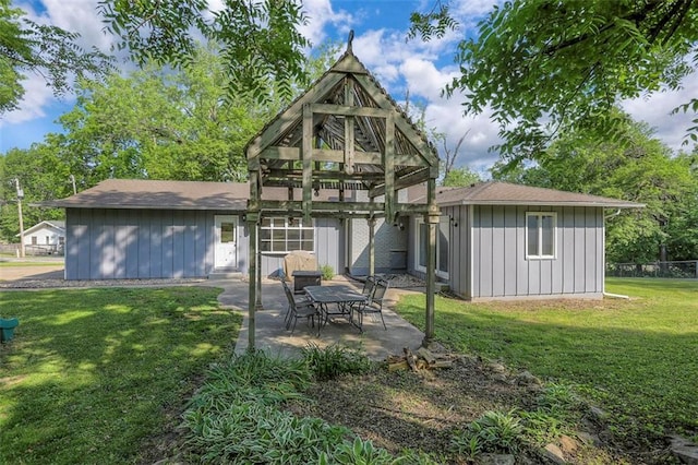 rear view of property with board and batten siding, a yard, and a patio area