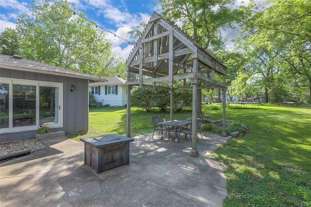 view of patio / terrace with a trampoline, outdoor dining area, and a fire pit