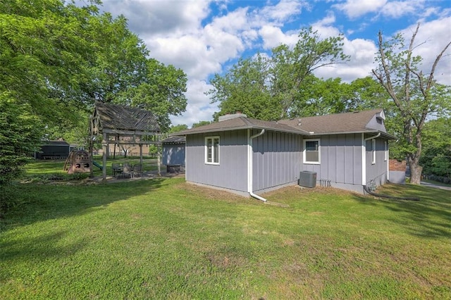 rear view of property with a lawn and central air condition unit