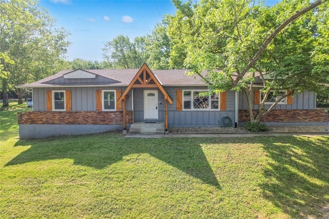 view of front of home featuring brick siding, board and batten siding, a front lawn, and a shingled roof