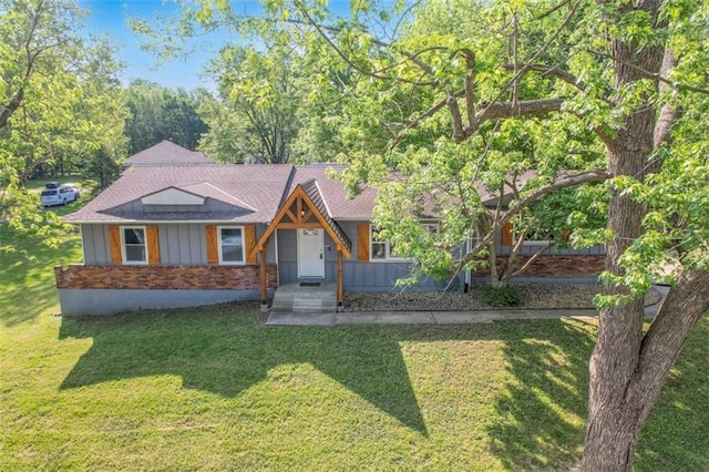 view of front of house featuring brick siding, a front lawn, board and batten siding, and a shingled roof