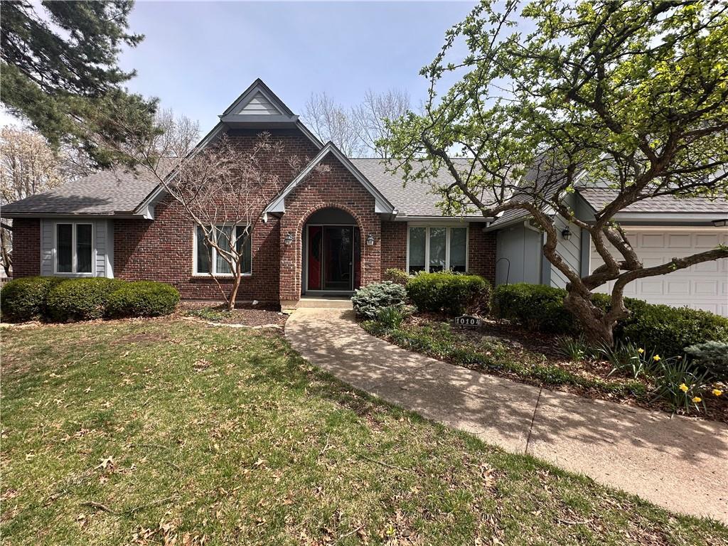view of front of house with brick siding, a front yard, and an attached garage