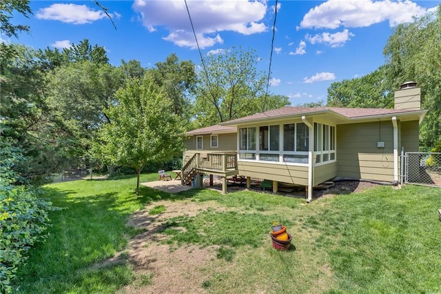 rear view of house featuring a sunroom, a chimney, and a deck