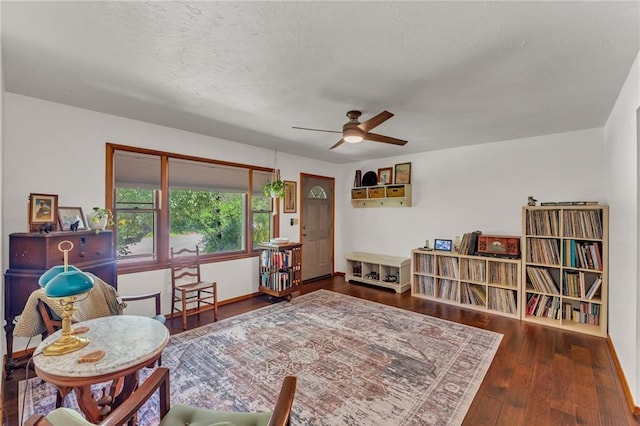 sitting room with ceiling fan, a textured ceiling, wood finished floors, and baseboards