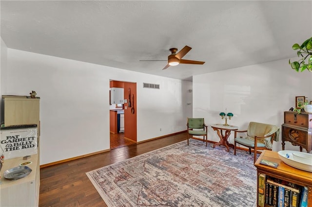 living area with a ceiling fan, wood-type flooring, and baseboards