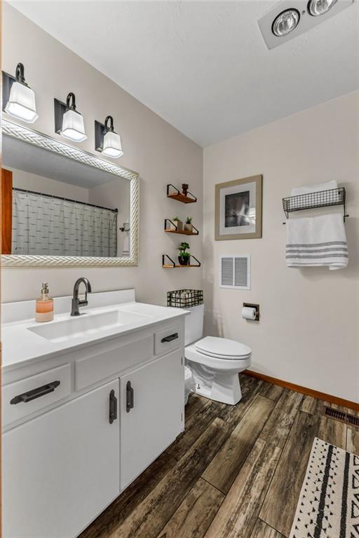 full bathroom with wood finished floors, toilet, vanity, baseboards, and a shower with curtain