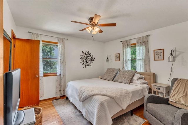 bedroom featuring multiple windows, light wood-type flooring, and ceiling fan