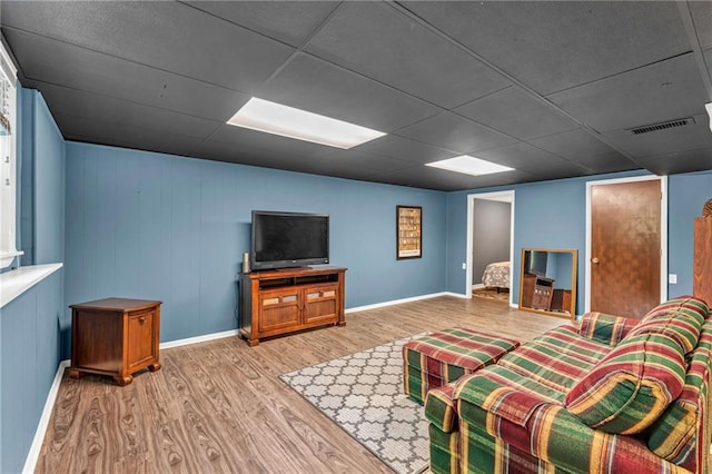 living room with wood finished floors, a drop ceiling, and baseboards