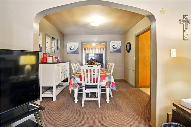 dining area featuring arched walkways and carpet
