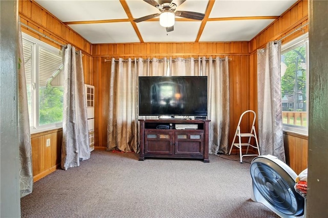 carpeted living room featuring wooden walls and ceiling fan