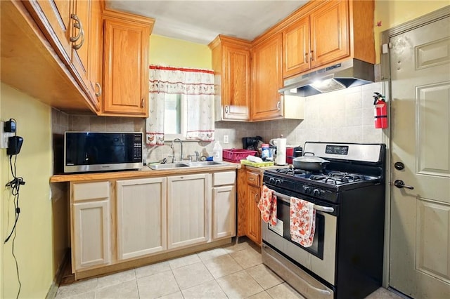 kitchen with stainless steel appliances, under cabinet range hood, a sink, light tile patterned floors, and backsplash