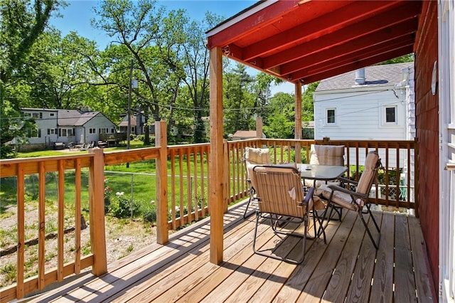 wooden terrace with outdoor dining area and a lawn