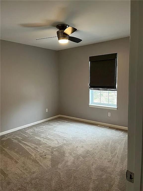 spare room featuring carpet, baseboards, and a ceiling fan