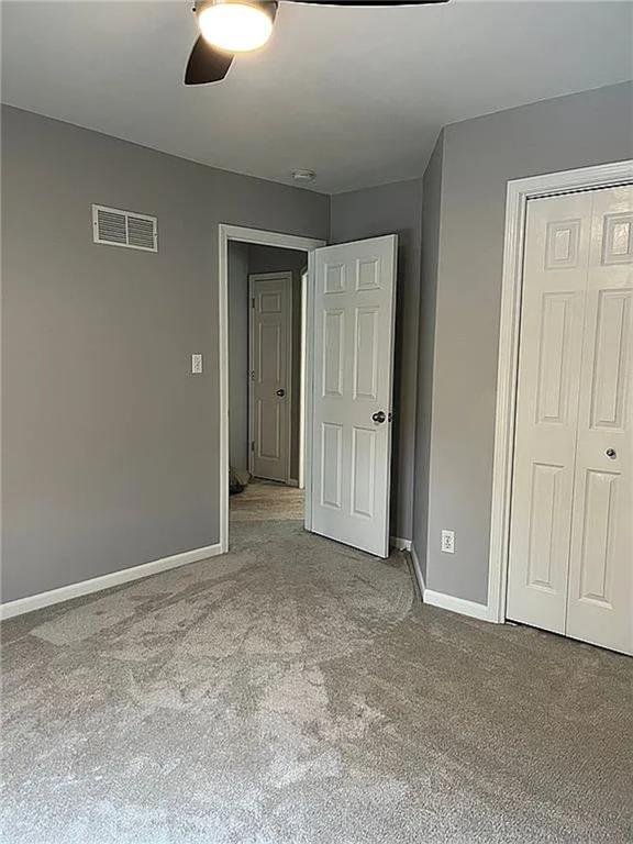 unfurnished bedroom with carpet, baseboards, a closet, and ceiling fan