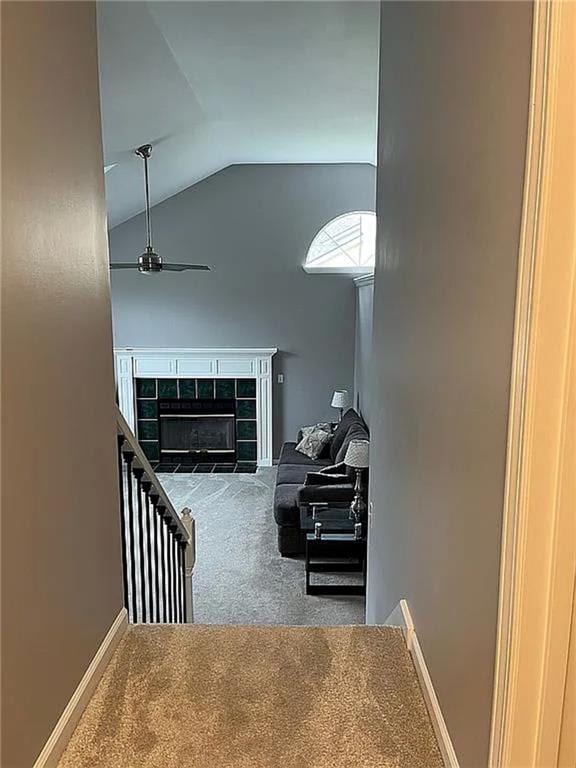 staircase with carpet floors, lofted ceiling, a fireplace, baseboards, and ceiling fan