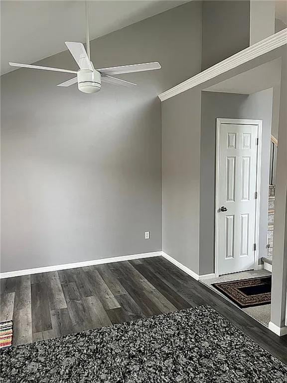 spare room featuring dark wood-style flooring, a ceiling fan, and baseboards