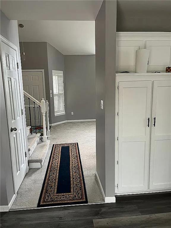 carpeted foyer featuring baseboards and stairs