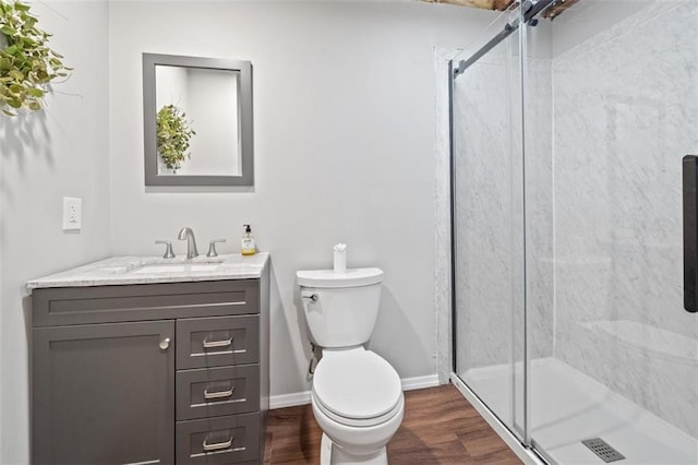 bathroom featuring wood finished floors, a stall shower, toilet, and vanity