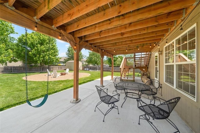 view of patio / terrace featuring stairway, a storage unit, an outbuilding, outdoor dining area, and a fire pit
