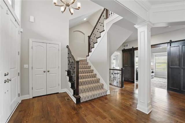8833 N Crescent Ave, Kansas City, MO 64157 - entrance foyer with a barn door, stairs, a chandelier, wood finished floors, and ornate columns