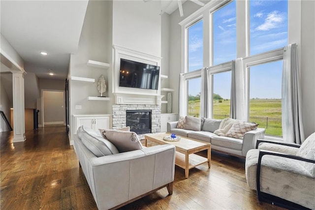 8833 N Crescent Ave, Kansas City, MO 64157 - living room with a high ceiling, plenty of natural light, a fireplace, dark wood-type flooring, and ornate columns