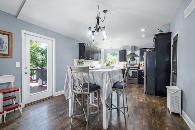 2251 Valley View Dr, Tonganoxie, KS 66086 - kitchen featuring appliances with stainless steel finishes, wall chimney exhaust hood, dark wood-type flooring, light countertops, and a kitchen breakfast bar