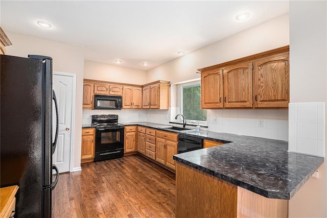 kitchen featuring black appliances, a sink, a peninsula, dark wood-style floors, and decorative backsplash