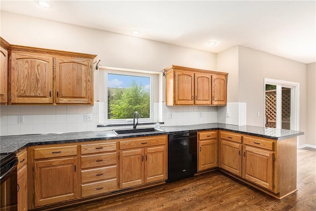kitchen featuring a sink, black appliances, a peninsula, dark wood-type flooring, and decorative backsplash