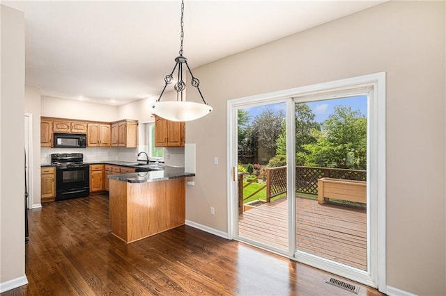 kitchen featuring black appliances, a peninsula, dark wood finished floors, backsplash, and baseboards