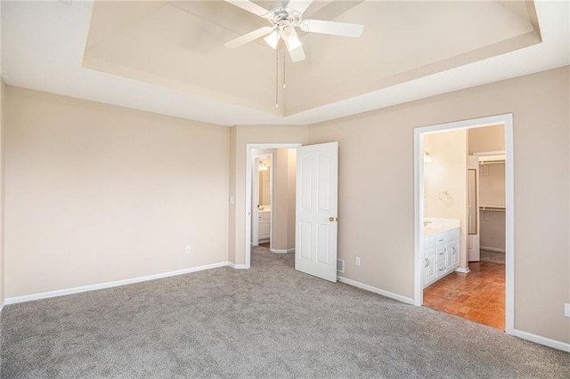unfurnished bedroom with a raised ceiling, light colored carpet, and baseboards