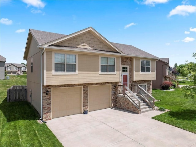 split foyer home featuring an attached garage, driveway, stone siding, a front yard, and roof with shingles