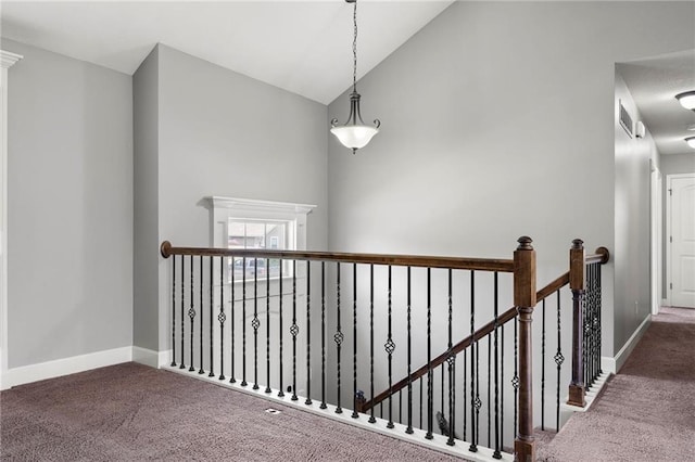 hallway featuring an upstairs landing, carpet, baseboards, and high vaulted ceiling