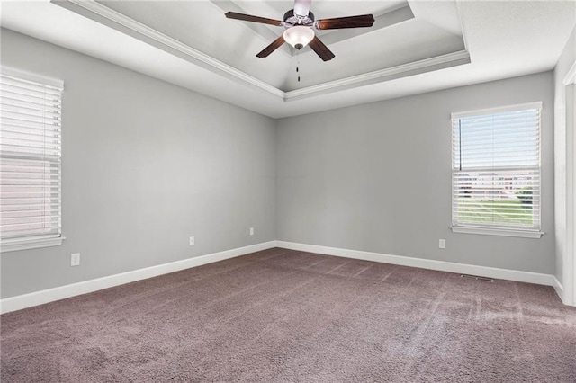 unfurnished room featuring a raised ceiling, dark carpet, ceiling fan, baseboards, and ornamental molding