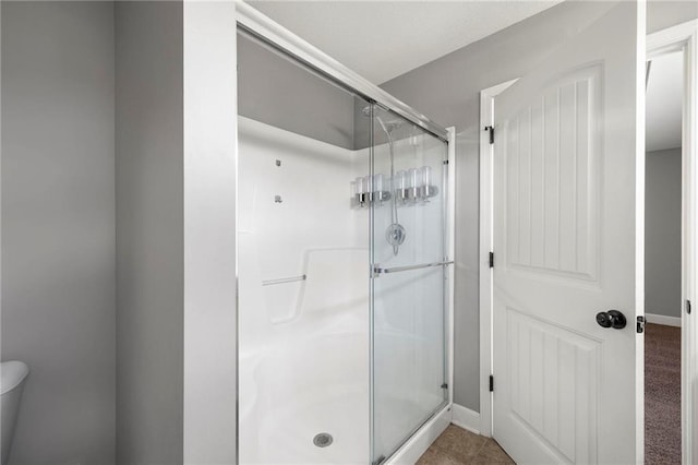 full bath with a shower stall and baseboards
