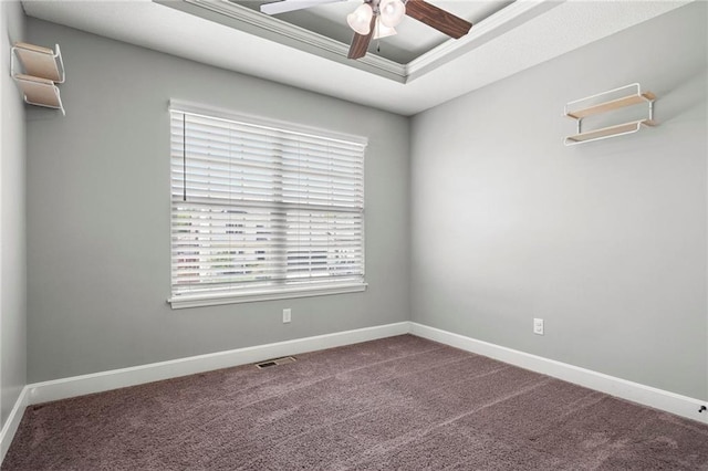 spare room featuring a ceiling fan, plenty of natural light, a tray ceiling, and carpet floors