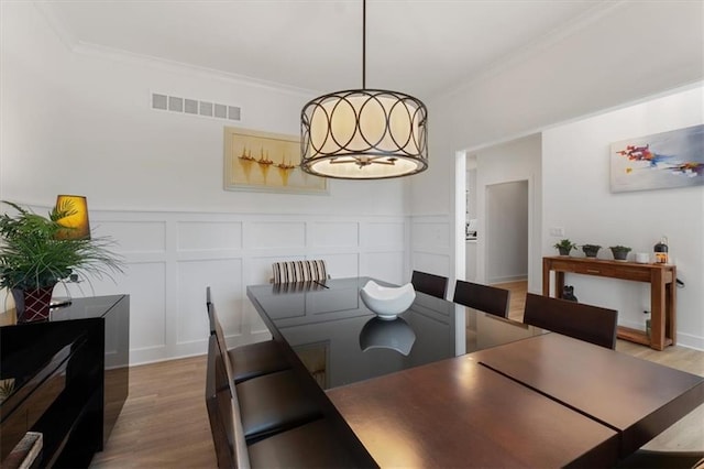 16521 S Stagecoach St, Olathe, KS 66062 - dining space featuring a decorative wall, light wood-type flooring, ornamental molding, and wainscoting