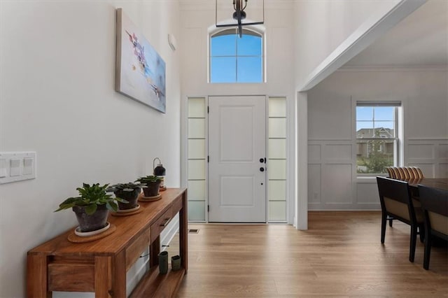 16521 S Stagecoach St, Olathe, KS 66062 - entrance foyer featuring light wood-type flooring, crown molding, a decorative wall, and a wainscoted wall