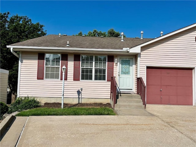 view of front of home featuring driveway, an attached garage, and roof with shingles
