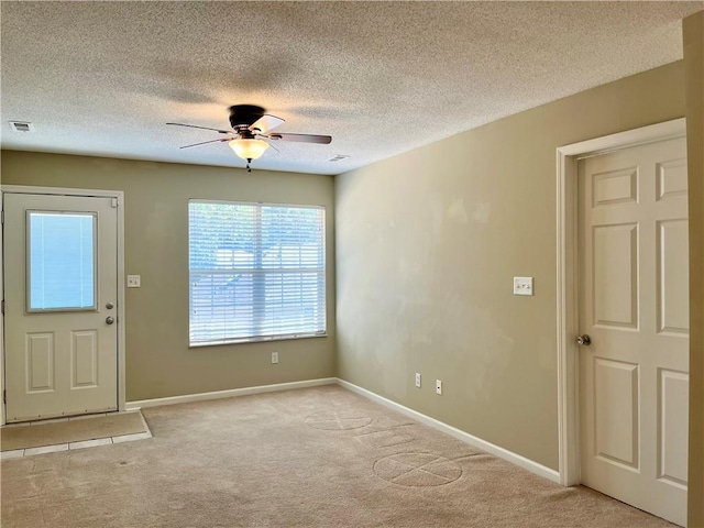 foyer entrance with light colored carpet, ceiling fan, a textured ceiling, and baseboards