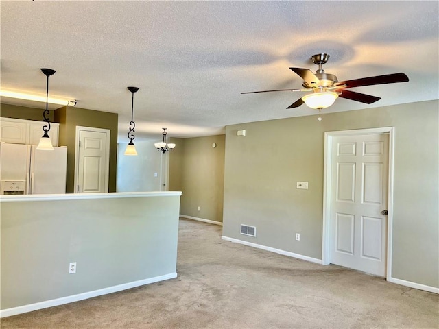 spare room with baseboards, ceiling fan, light colored carpet, and a textured ceiling