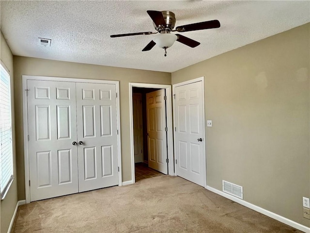 unfurnished bedroom featuring light colored carpet, baseboards, a closet, and a textured ceiling