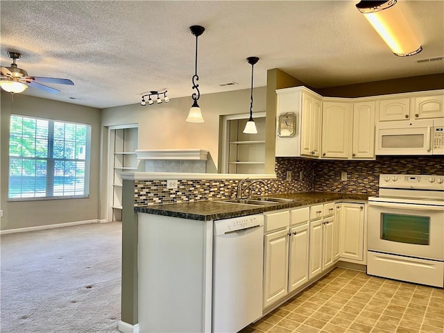 kitchen featuring white appliances, a peninsula, a sink, ceiling fan, and dark countertops