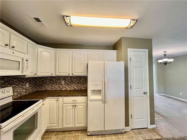 kitchen featuring white appliances, dark countertops, white cabinets, a chandelier, and tasteful backsplash