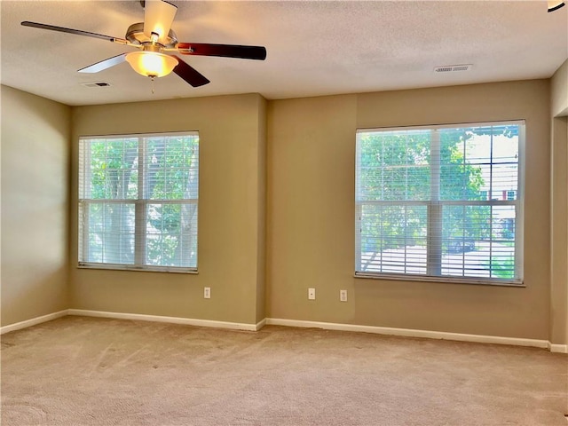 unfurnished room with light colored carpet, baseboards, a ceiling fan, and a textured ceiling
