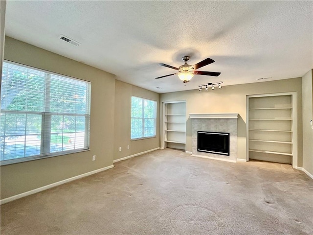 unfurnished living room with a textured ceiling, baseboards, a fireplace with flush hearth, ceiling fan, and built in features